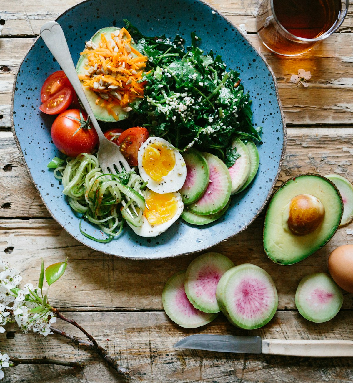 Ausgewogene Schale mit Gemüse, Ei und Avocado auf einem Holztisch